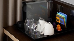 A tray with a coffee maker, a white teapot, and several cups on a wooden table. - Premier Inn Manchester Salford Quays (Salford)