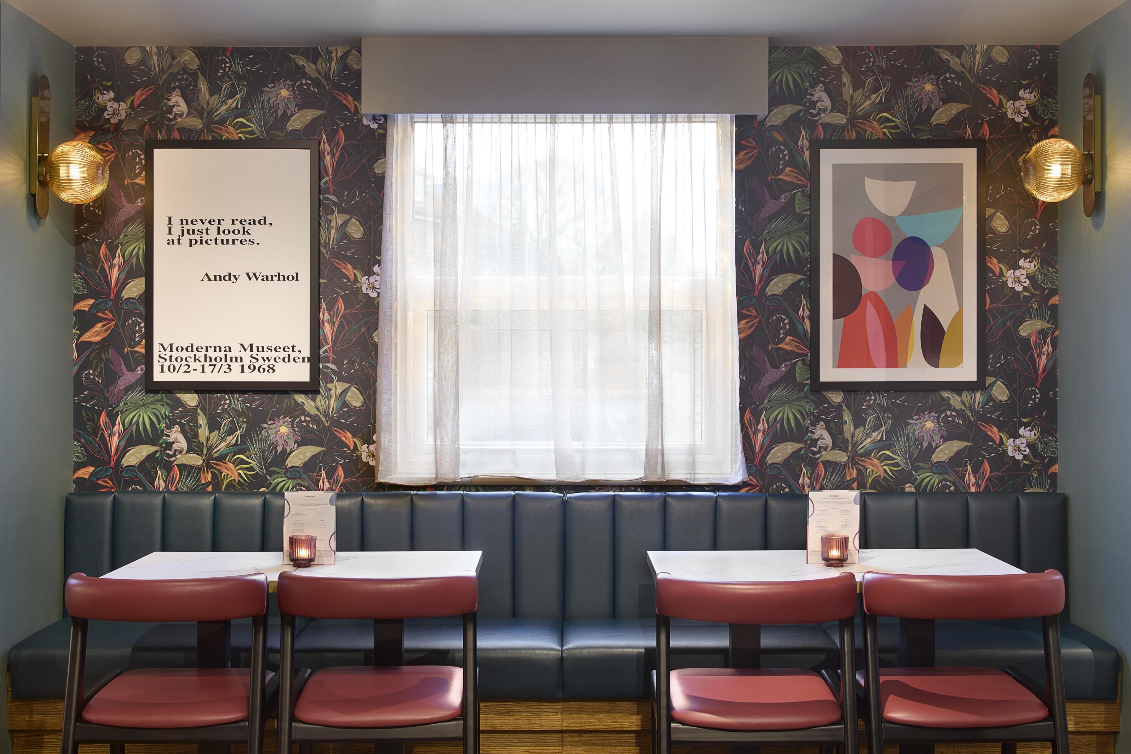 Un interior de restaurante con zona de cabinas, mesas y decoración en las paredes.