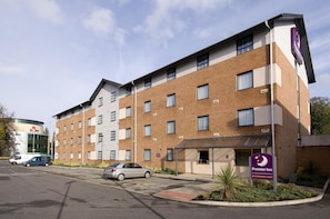 Un hotel con fachada de ladrillo, un estacionamiento y un letrero de Premier Inn.