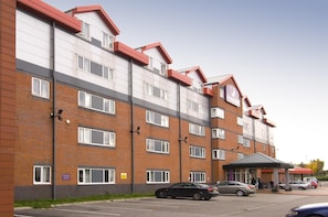 A multi-story hotel with a brick facade, multiple windows, and a covered entrance area. - Premier Inn Manchester Old Trafford (Manchester)