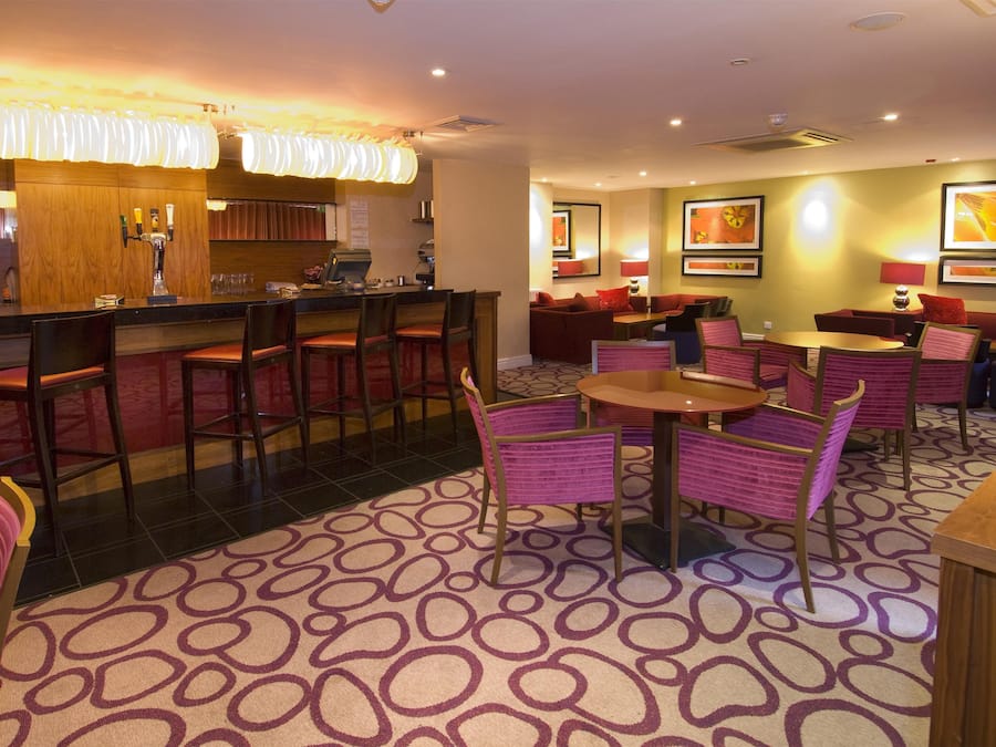 Eine Hotelhalle mit Barbereich, Sitzgelegenheiten und Kunstwerken an den Wänden.