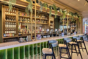 Un espace bar avec des étagères remplies de bouteilles, de verres et d’ustensiles de bar. On y trouve des tabourets de bar et un comptoir.