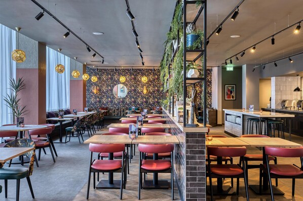 A restaurant with multiple tables and chairs, a counter, and a wall with a decorative pattern.