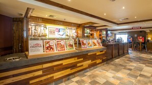 Ein Essensausgabebereich mit Speisekarten, einer Bar und einem Schild, das Costa als Servicepunkt kennzeichnet.