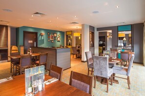A hotel lobby with a reception desk, dining area, and bar. - Premier Inn Manchester City Centre West (Salford)