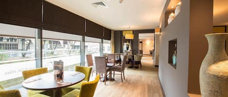 A modern hotel room with a dining area, large windows, and a large vase.