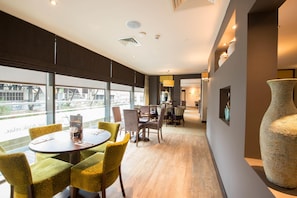 A modern hotel room with a dining area, large windows, and a large vase. - Premier Inn Manchester City Centre West (Salford)