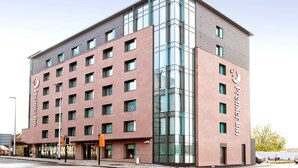 Un hotel de varios pisos con una fachada de vidrio destacada, techo plano y una serie de ventanas.