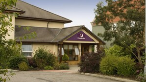 Un hotel con un letrero que dice 'Premier Inn', una entrada principal y follaje circundante.