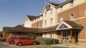 Un hôtel reconnaissable à son enseigne Premier Inn bien visible, un parking avec des places délimitées et une façade en briques.