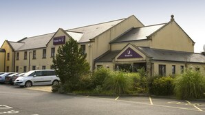 Ein Hotel mit einem Schild, auf dem 'Premier Inn' steht, und einem Parkplatz mit Autos.