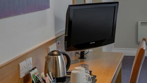 A hotel room with a wooden desk, a Samsung TV, a coffee maker, two mugs, a tray with a magazine holder, and a glass of water. - Embassy Hotel, Newcastle-Gateshead, Team Valley, Sure Hotel Collection by Best Western (Gateshead)