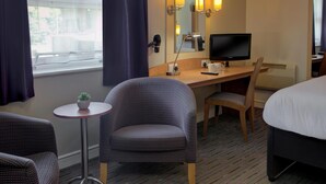 A hotel room with a bed, a desk with a computer, a chair, a small table with a plant, and a window with curtains. - Embassy Hotel, Newcastle-Gateshead, Team Valley, Sure Hotel Collection by Best Western (Gateshead)