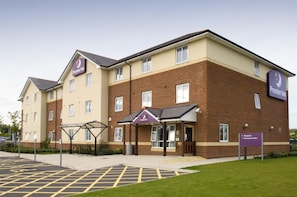 Un hotel Premier Inn con fachada de ladrillo, un acceso cubierto y un área de estacionamiento.