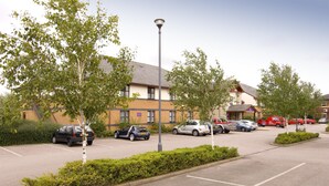A parking lot with cars, a street lamp, and buildings in the background. - Premier Inn Leicester - Braunstone (Leicester)