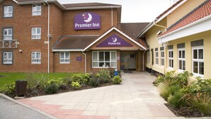 A Premier Inn hotel with a brick facade, a clear entrance, and a landscaped garden area.