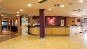 Ein Hotel-Empfangsbereich mit einem gut sichtbaren Premier Inn Schild, einer Rezeption und einer Säule.