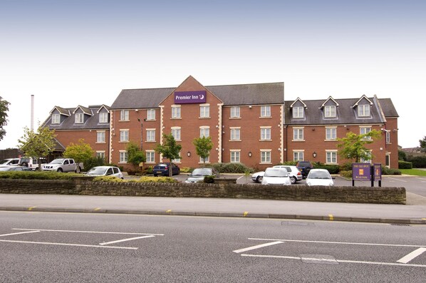 Een hotel met een bakstenen gevel, meerdere ramen en een bord waarop staat dat het een Premier Inn is.