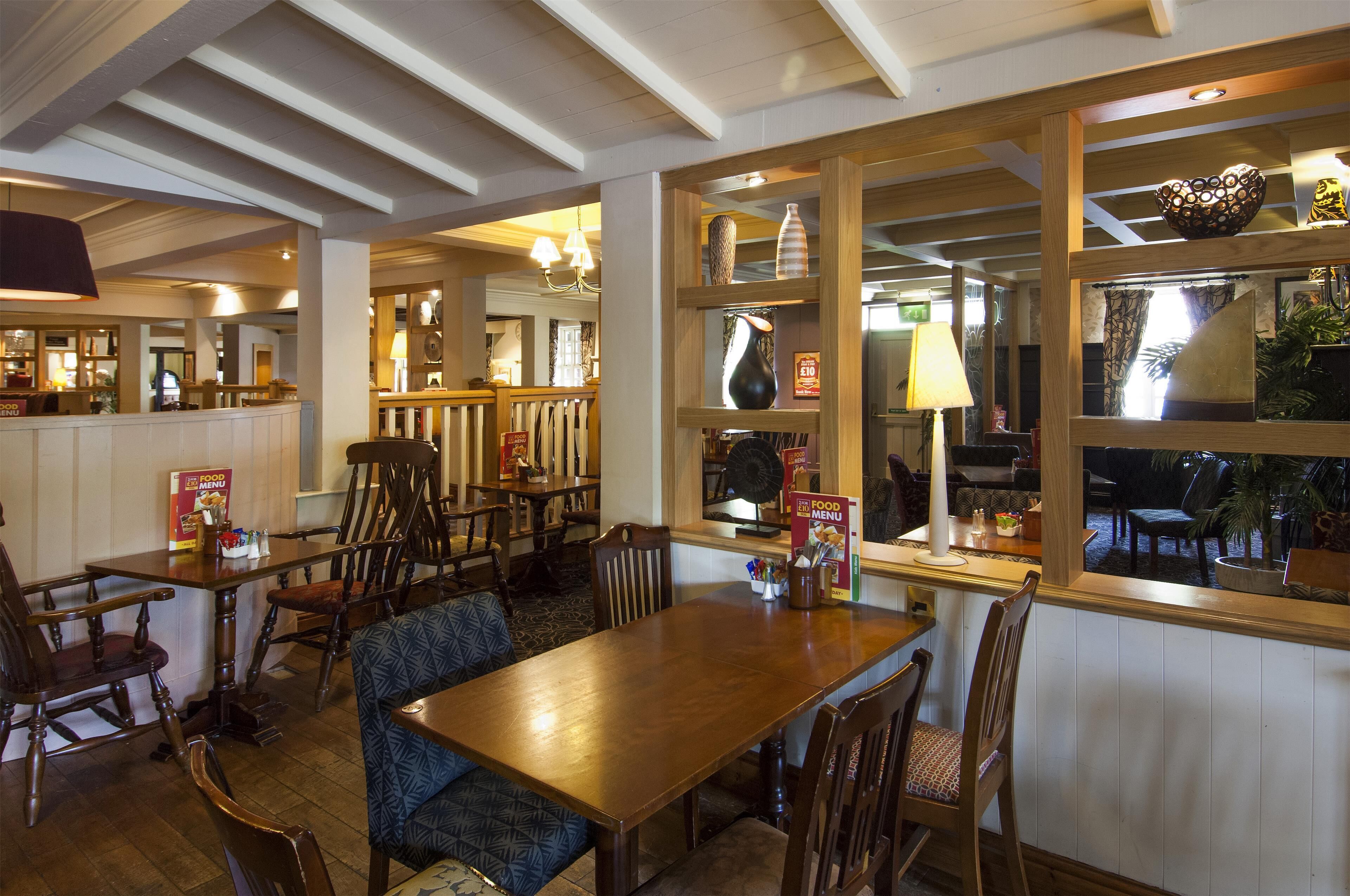 A restaurant interior with wooden furniture, a menu stand, and a window with a view.