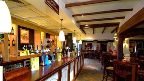 Uma área de bar com várias torneiras, balcão e assentos.