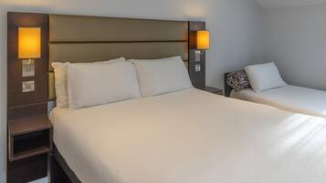 A hotel room with a large bed, two bedside tables, and wall-mounted lamps.