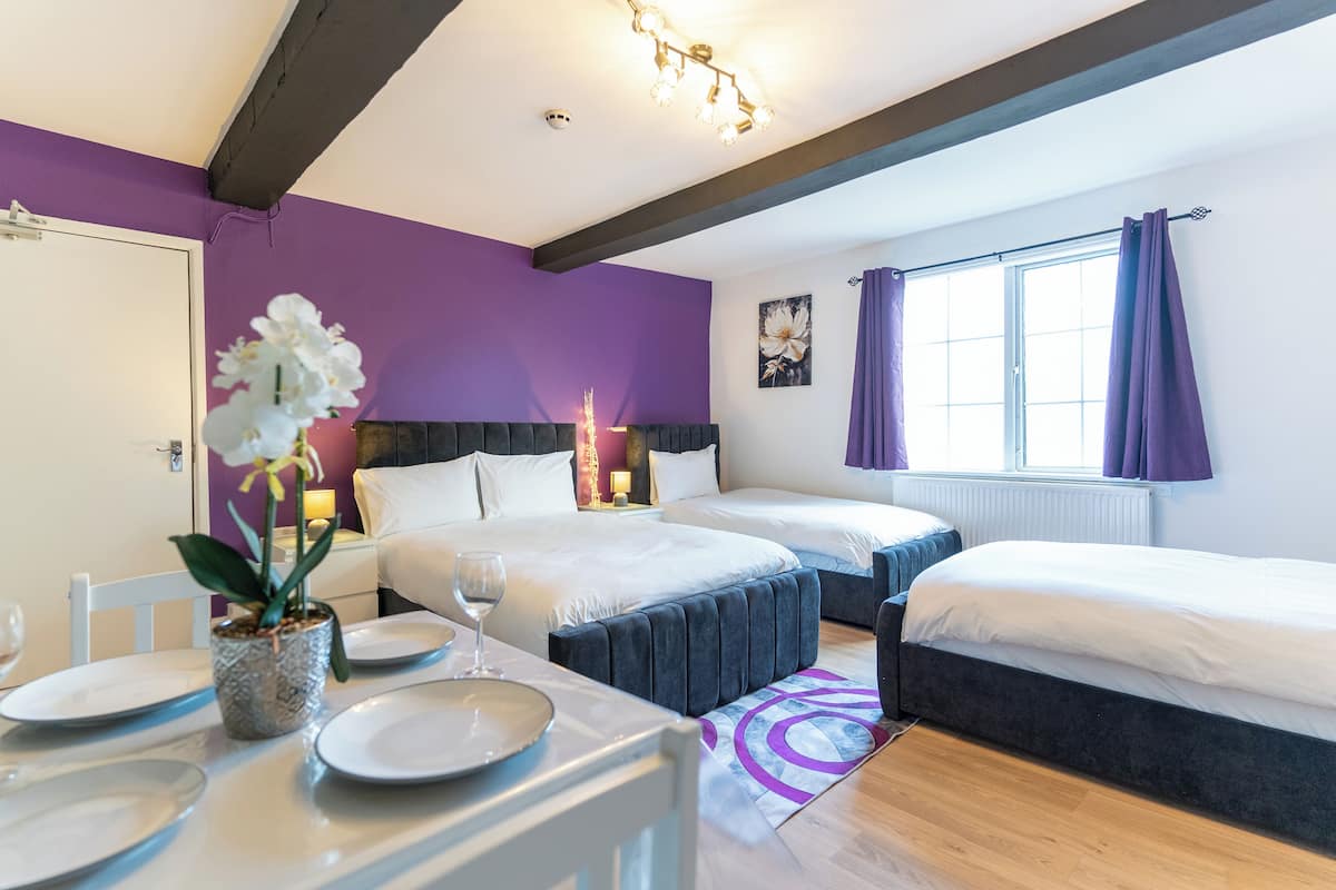 A hotel room with two beds, a dining table with plates and a wine glass, and a potted plant.