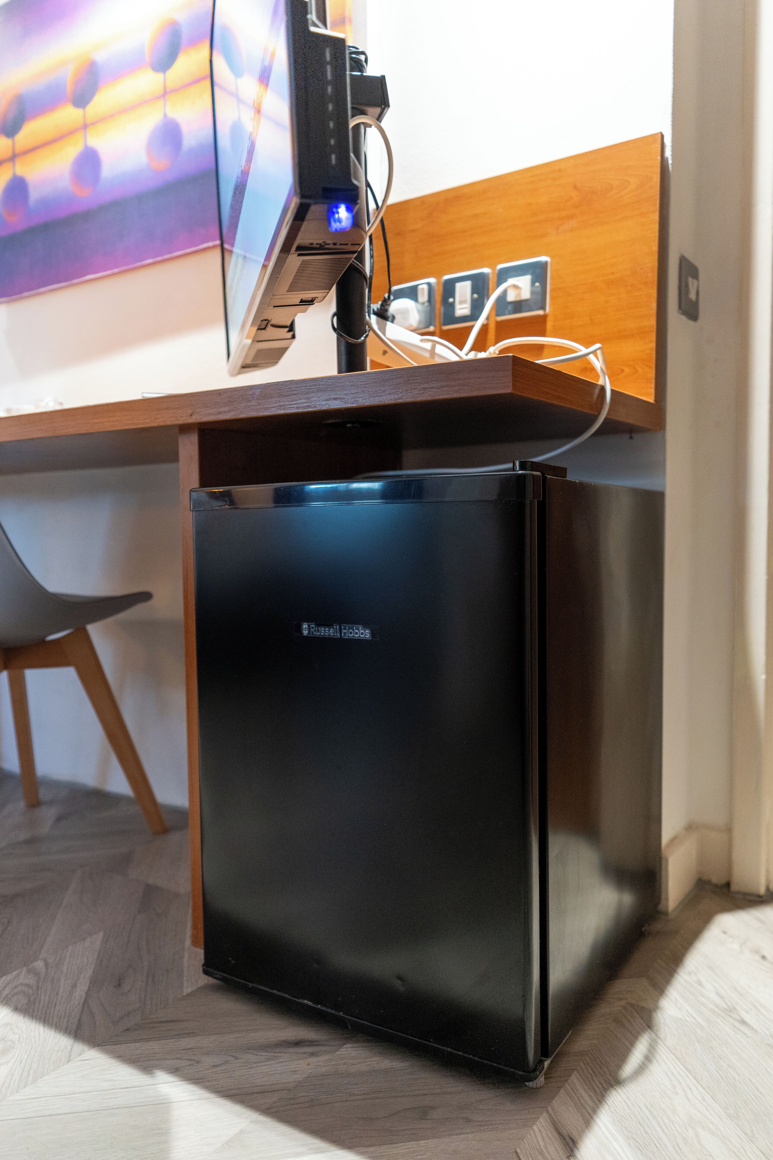 A compact black refrigerator with a digital display and a wooden countertop above it.