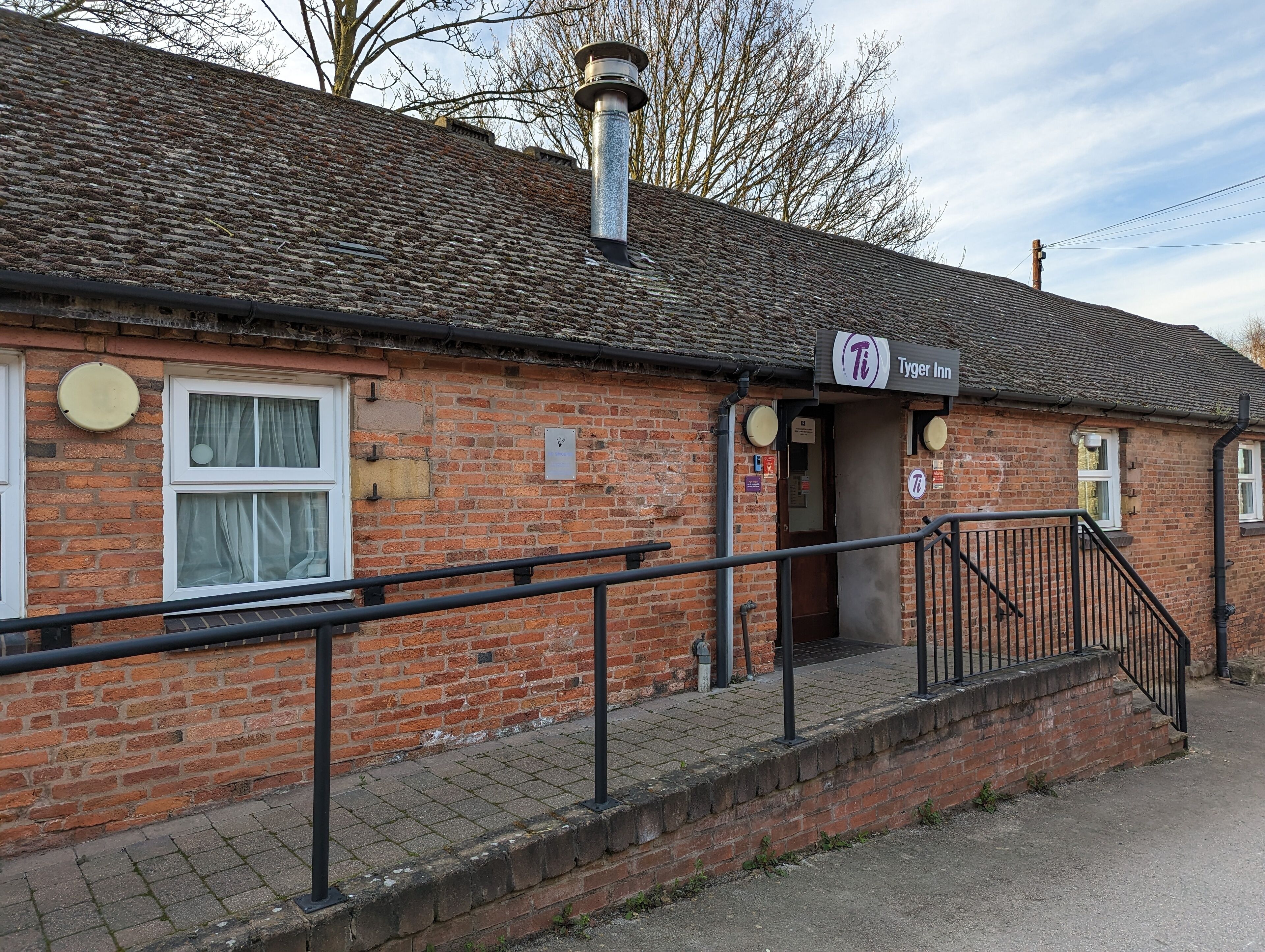 A brick building with a sign for 'Tyger Inn'.