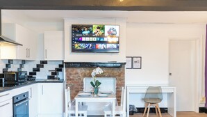 Een moderne keuken met witte kasten, een metselwerk open haard en een eethoek met een tafel en stoelen.