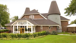 A brick building with a large chimney, a covered entrance, and a lawn area. - Premier Inn Derby South (Derby)