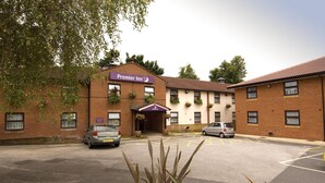 Un hôtel avec une enseigne indiquant « Premier Inn », un parking et un bâtiment aux murs en briques et aux fenêtres.
