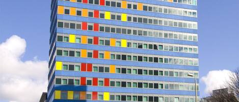 A multi-story hotel with a modern design, featuring a prominent logo at the ground level.