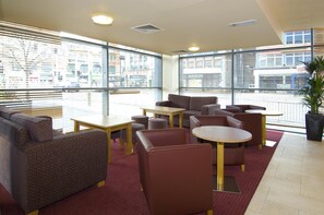 A modern lounge area with seating, tables, and large windows offering city views. - Premier Inn Leicester City Centre - Train Station (Leicester)