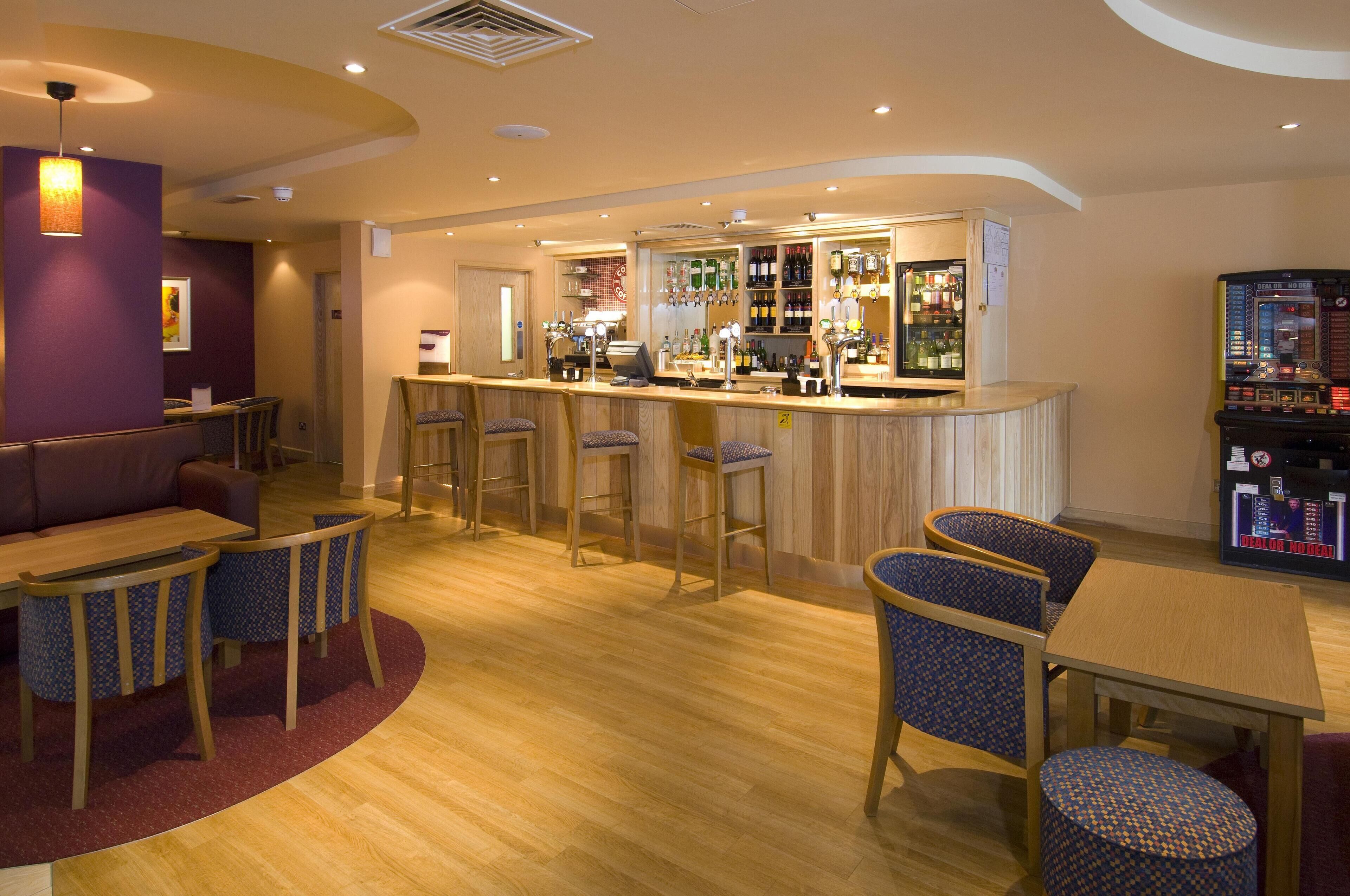 A bar area with stools, a counter, and a selection of bottles.