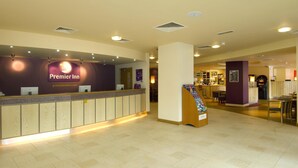En hotellreception med en disk, en informationskatalog och en bar i bakgrunden.