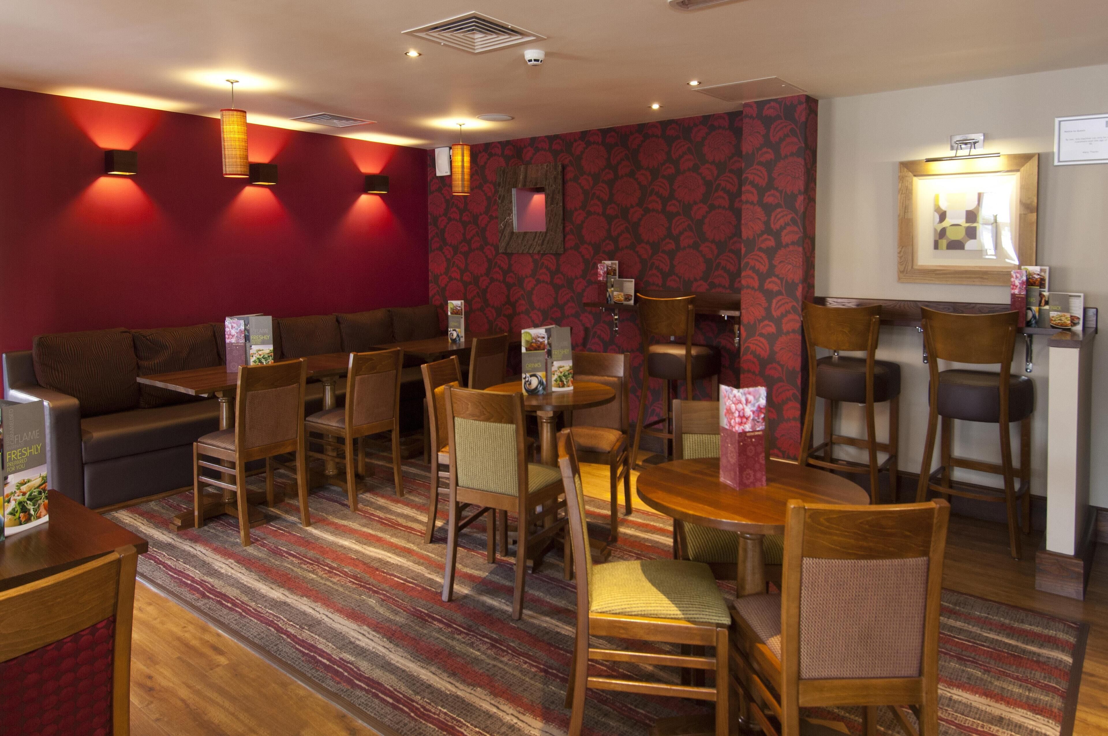A hotel room with a sofa, dining table, chairs, and a patterned wall.