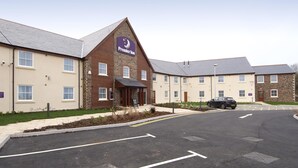 A hotel with a prominent Premier Inn sign, a parking area, and a well-maintained lawn. - Premier Inn Camborne (Camborne)