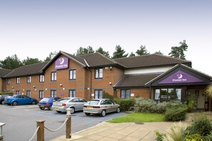 A Premier Inn hotel with a brick facade, multiple parking spaces, and a well-maintained garden area. - Premier Inn Norwich West - Showground/A47 (Norwich)