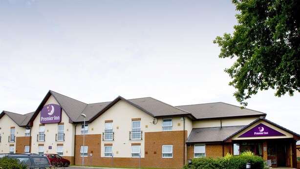 A Premier Inn hotel with a brick facade, multiple windows, and a parking lot. - Premier Inn Norwich Airport (Norwich)
