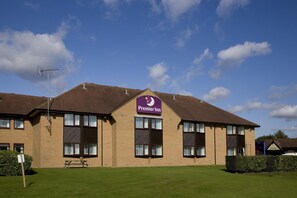 Un hotel Premier Inn con cielo despejado, césped y una mesa de picnic.