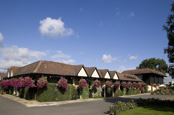 Eine Reihe von Hotelgebäuden mit einheitlichem Baustil, mit Satteldächern und mehreren hängenden Blumenkörben.