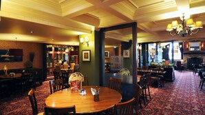 A restaurant with a wooden table, chairs, and a patterned carpet. - Premier Inn Northampton South - Wootton (Northampton)