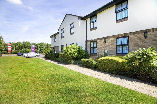 A modern building with a flat roof, large windows, and a well-maintained lawn. - Premier Inn Northampton South - Wootton (Northampton)