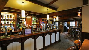 A bar area with multiple taps, a counter, and seating. - Premier Inn Northampton South - Wootton (Northampton)