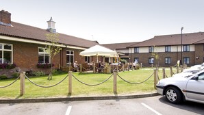 A building with a brick facade, a white tent, and a parked car. - Premier Inn Oxford South - Didcot (Abingdon)