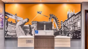 Un comptoir d’accueil doté d’un écran numérique, une enseigne Premier Inn et une fresque représentant un paysage urbain.