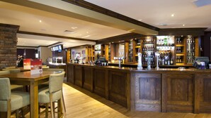 Eine Bar mit Holztresen, Barhocker und einer Speisekarte.