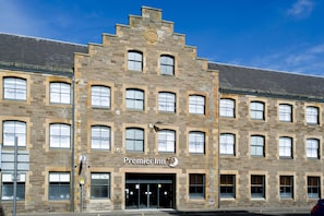 Un bâtiment en briques avec l’enseigne « Premier Inn », de nombreuses fenêtres et un ciel dégagé.