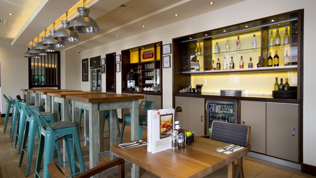 Een bar met verschillende zitplaatsen, een minibar en een selectie aan drankjes.