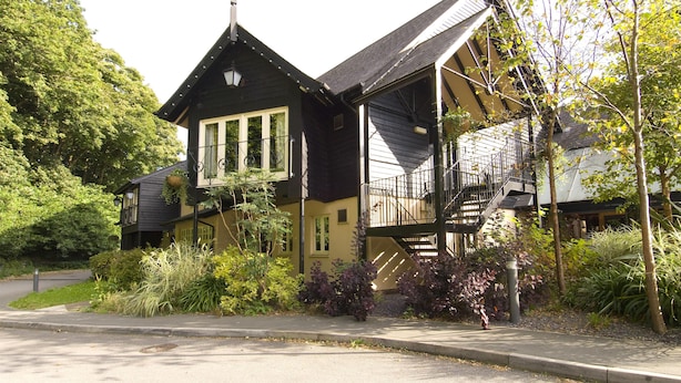 Un bâtiment à deux étages doté d’un balcon, d’un escalier et d’un espace jardin.